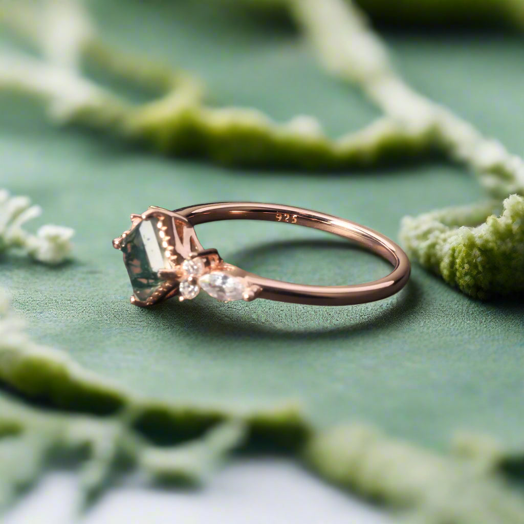 Rose gold ring with a green gemstone on a dark surface