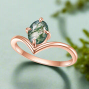 Rose gold ring with a green gemstone on a white background