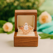 Rose gold ring with a large diamond in a wooden box against a blurred natural background