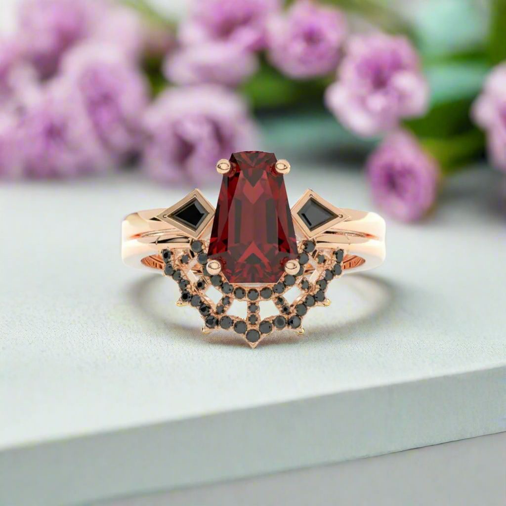 Rose gold ring with a red gemstone and black gemstones on a white background