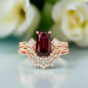Rose gold ring with a red gemstone and diamond accents on a blurred floral background