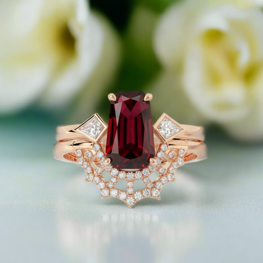 Rose gold ring with a red gemstone and diamond accents on a blurred floral background