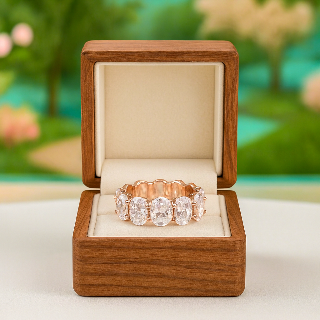 Rose gold ring with clear stones in a wooden box against a blurred natural background