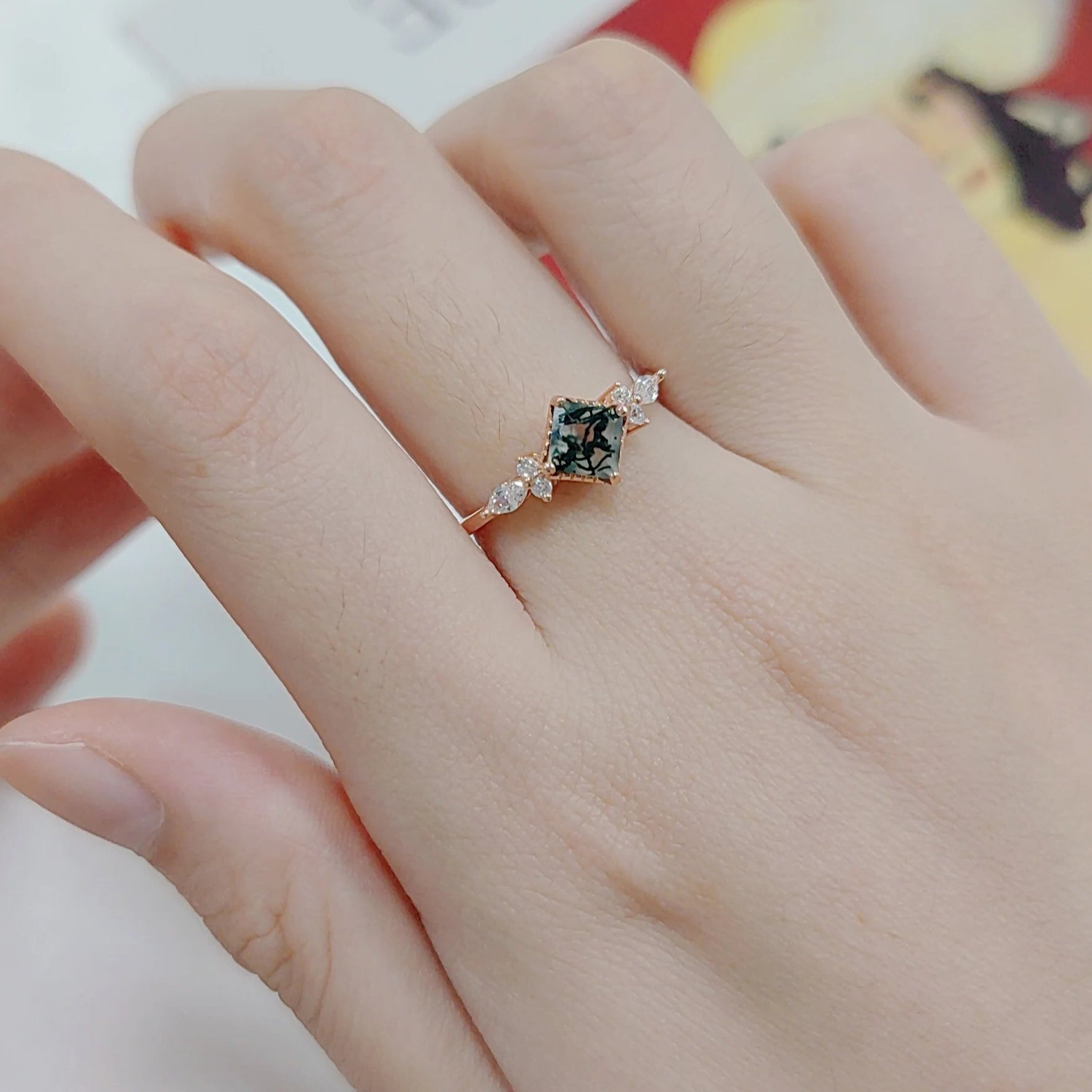Rose gold ring with green gemstone and small diamonds on a dark surface