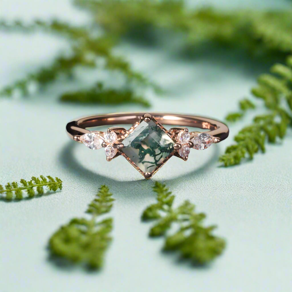 Rose gold ring with green gemstone and small diamonds on a dark surface