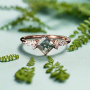 Rose gold ring with green gemstone and small diamonds on a dark surface