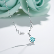 Silver antler-shaped necklace with a blue gemstone on a blue background