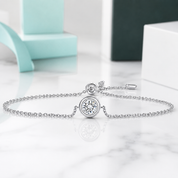 Silver bracelet with a round pendant on a light surface