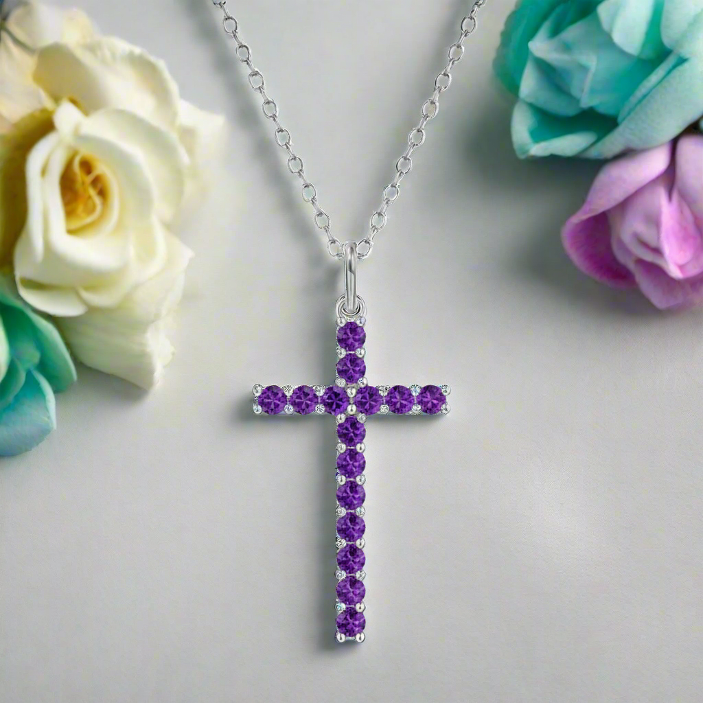 Silver cross necklace with purple gemstones on a white background
