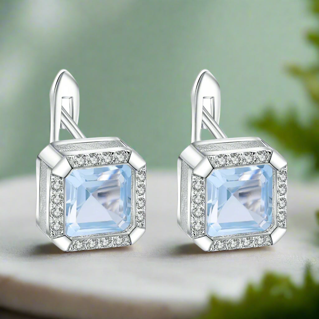Silver earrings with blue gemstones on a white background