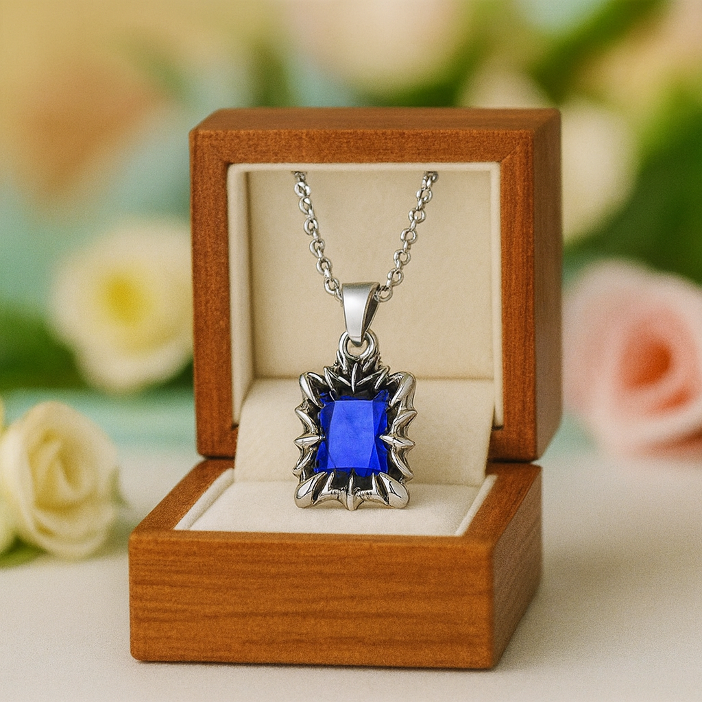 Silver necklace with a blue pendant in an open wooden box with flowers in the background