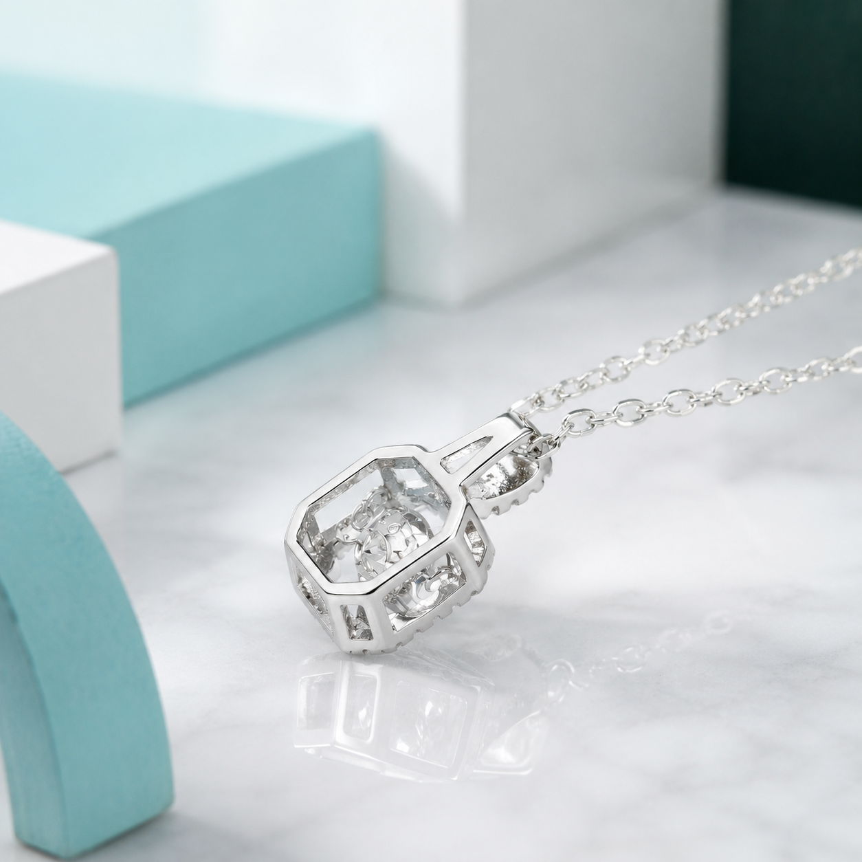 Silver necklace with a diamond pendant on a light gray surface.