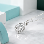 Silver necklace with a diamond pendant on a light gray surface.