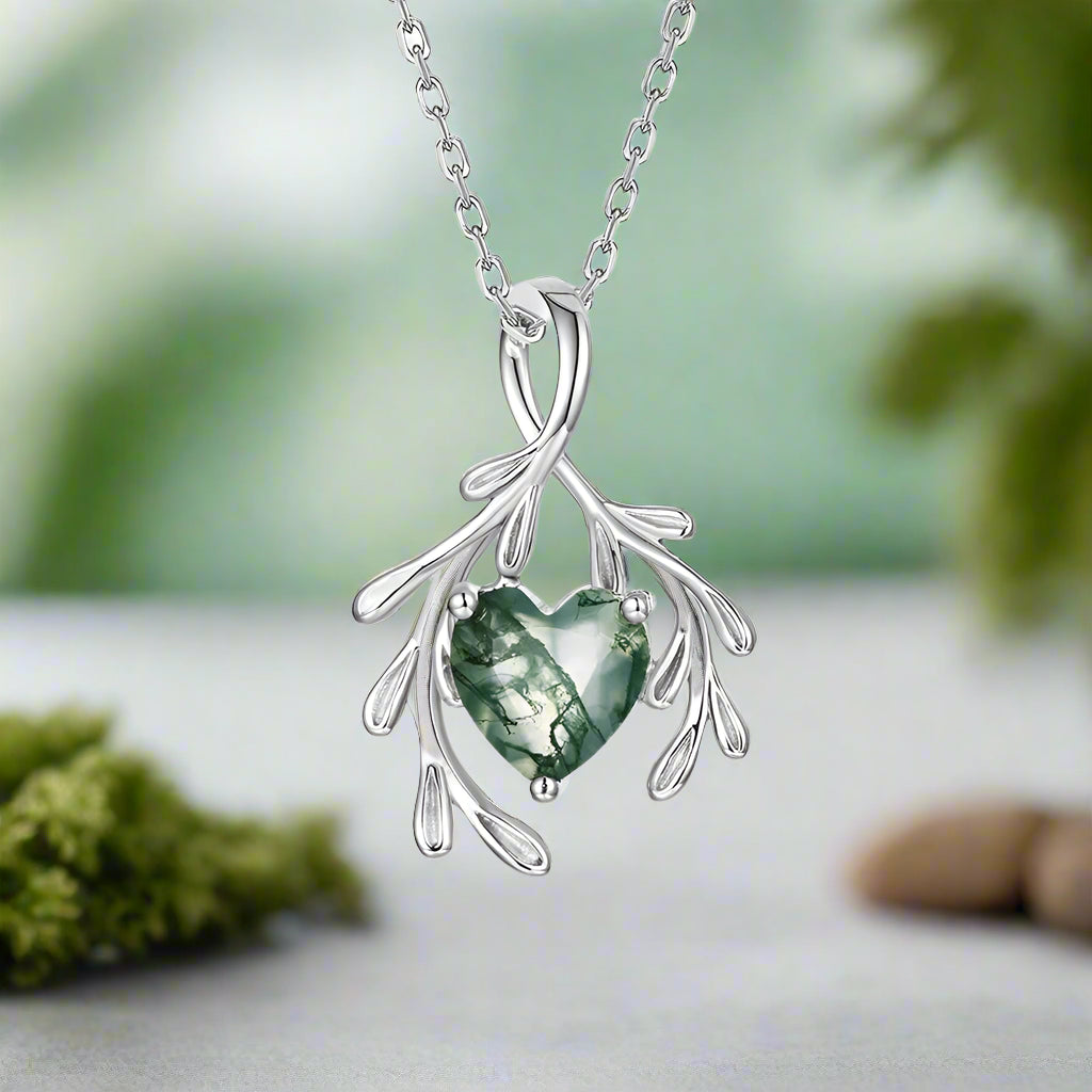 Silver necklace with a green heart-shaped pendant on a white background