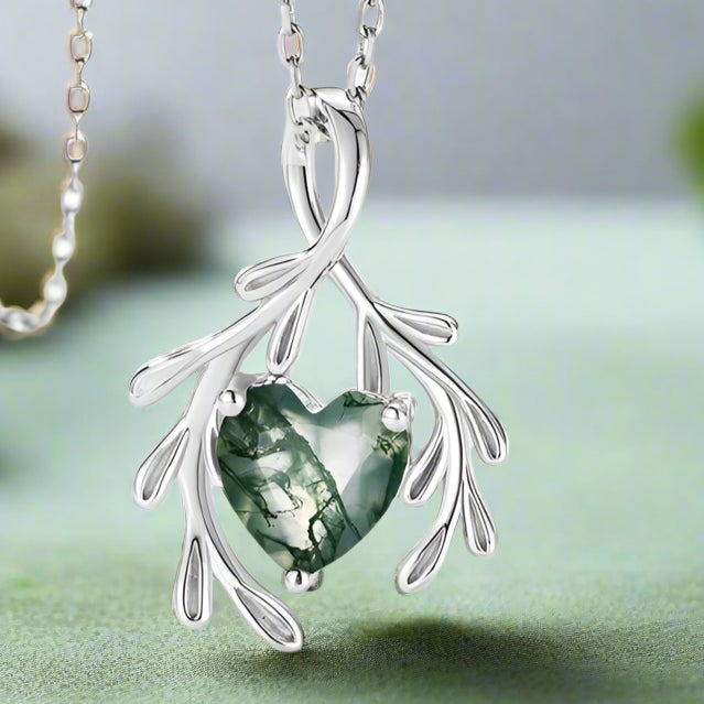 Silver necklace with a green heart-shaped pendant on a white background