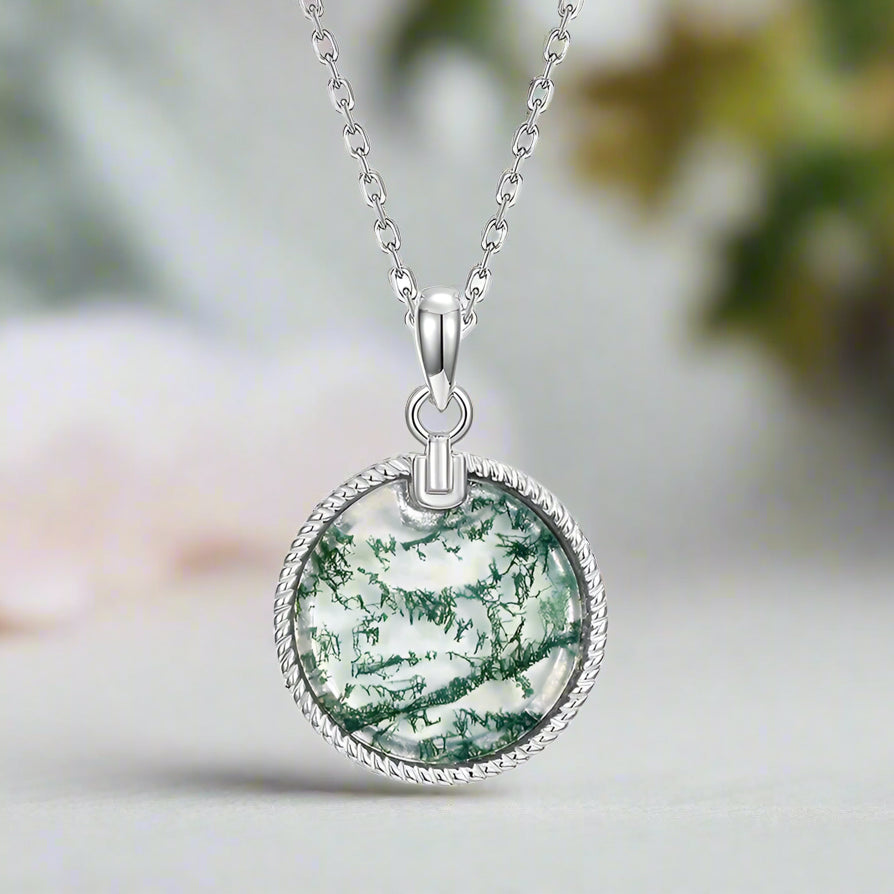 Silver necklace with a green stone pendant on a white background