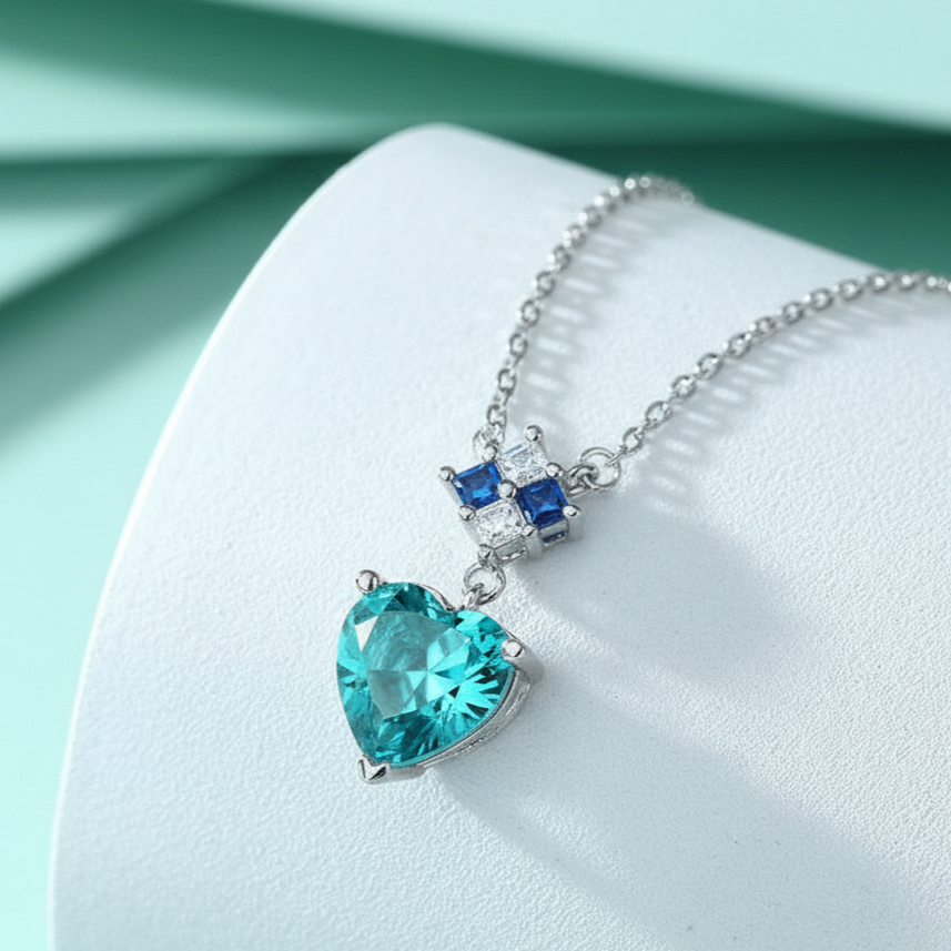 Silver necklace with a heart-shaped blue gemstone pendant on a light blue background