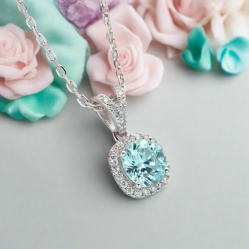 Silver necklace with a light blue gemstone pendant on a pink and gray background