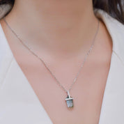 Silver necklace with a pendant on a person wearing a white blazer