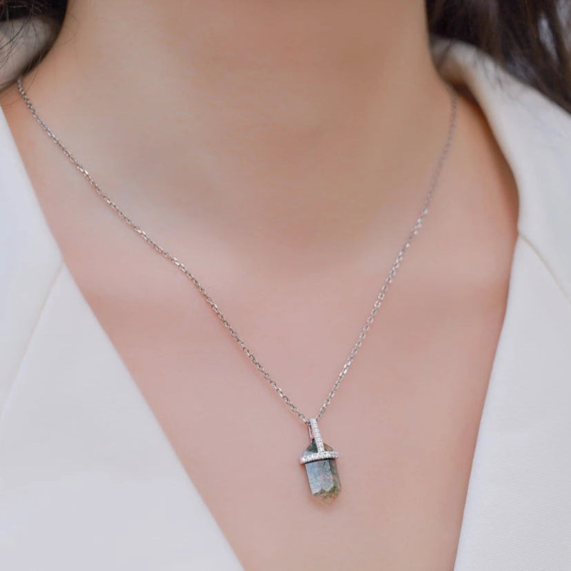Silver necklace with a pendant on a person wearing a white blazer