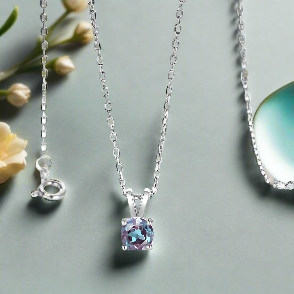 Silver necklace with a purple gemstone pendant on a light gray background