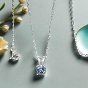 Silver necklace with a purple gemstone pendant on a light gray background