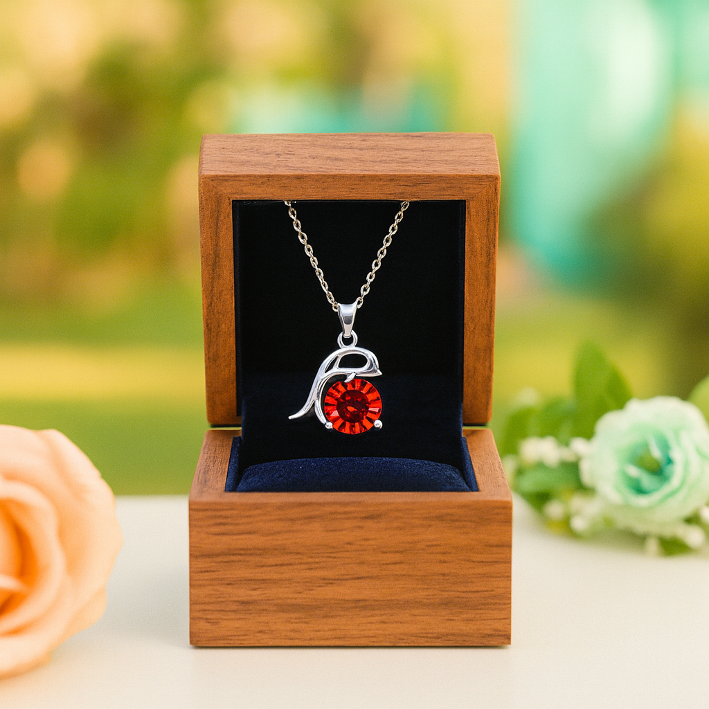Silver necklace with a red pendant in a wooden box with a blurred green background