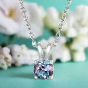 Silver necklace with a round gemstone pendant on a white background
