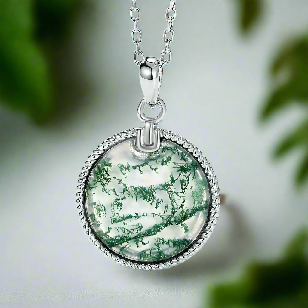 Silver necklace with a round pendant featuring green and white patterns on a light blue background.