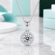 Silver necklace with a round pendant on a reflective surface