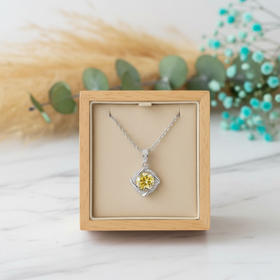 Silver necklace with a yellow gemstone in a wooden box on a light background