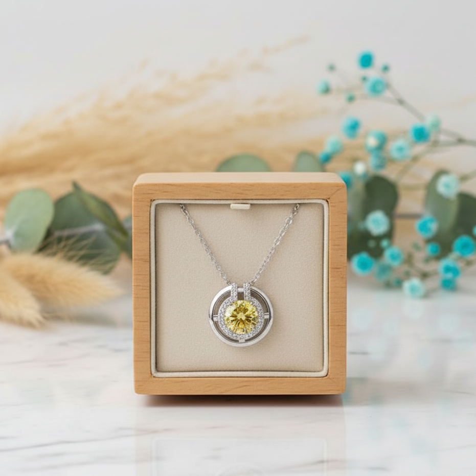 Silver necklace with a yellow gemstone in a wooden box on a light background