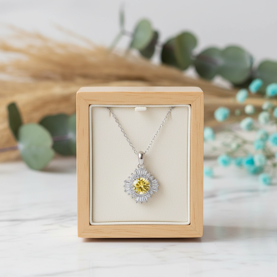 Silver necklace with a yellow pendant in a wooden box on a light background