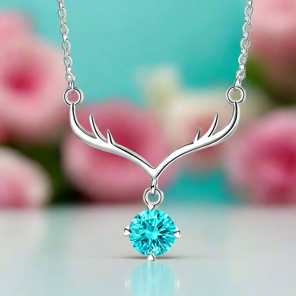 Silver necklace with antler design and turquoise gemstone against a blurred floral background