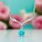 Silver necklace with antler design and turquoise gemstone against a blurred floral background