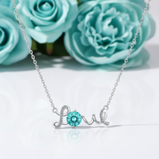 Silver necklace with 'love' pendant featuring a blue gemstone on a white background