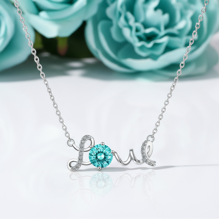 Silver necklace with 'love' pendant featuring a blue gemstone on a white background