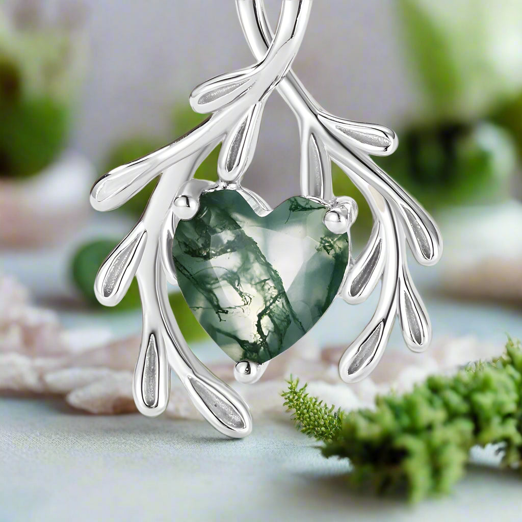 Silver pendant with a green heart-shaped gem on a white background