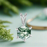 Silver pendant with a green stone on a white background