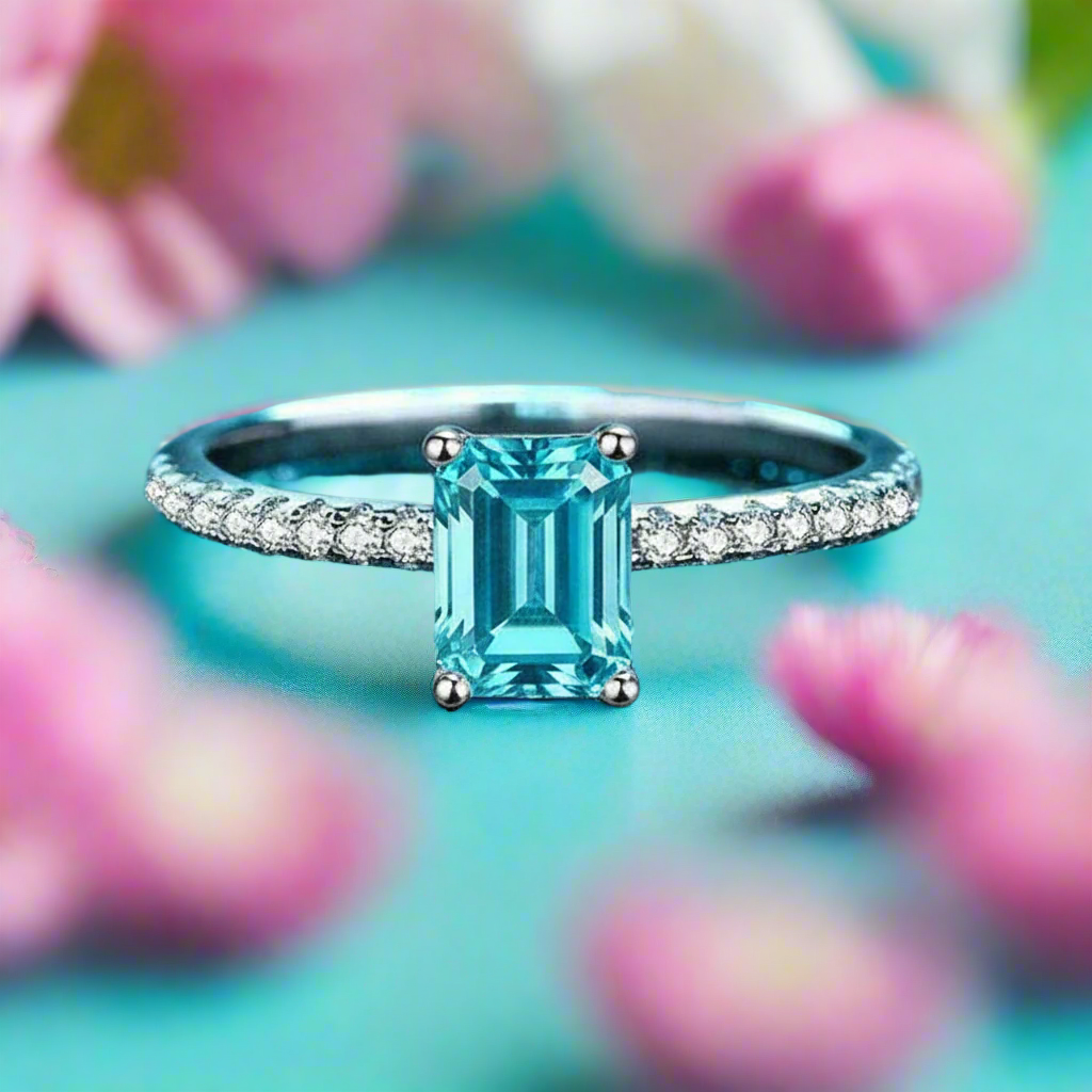 Silver ring with a blue gemstone on a blue glittery background