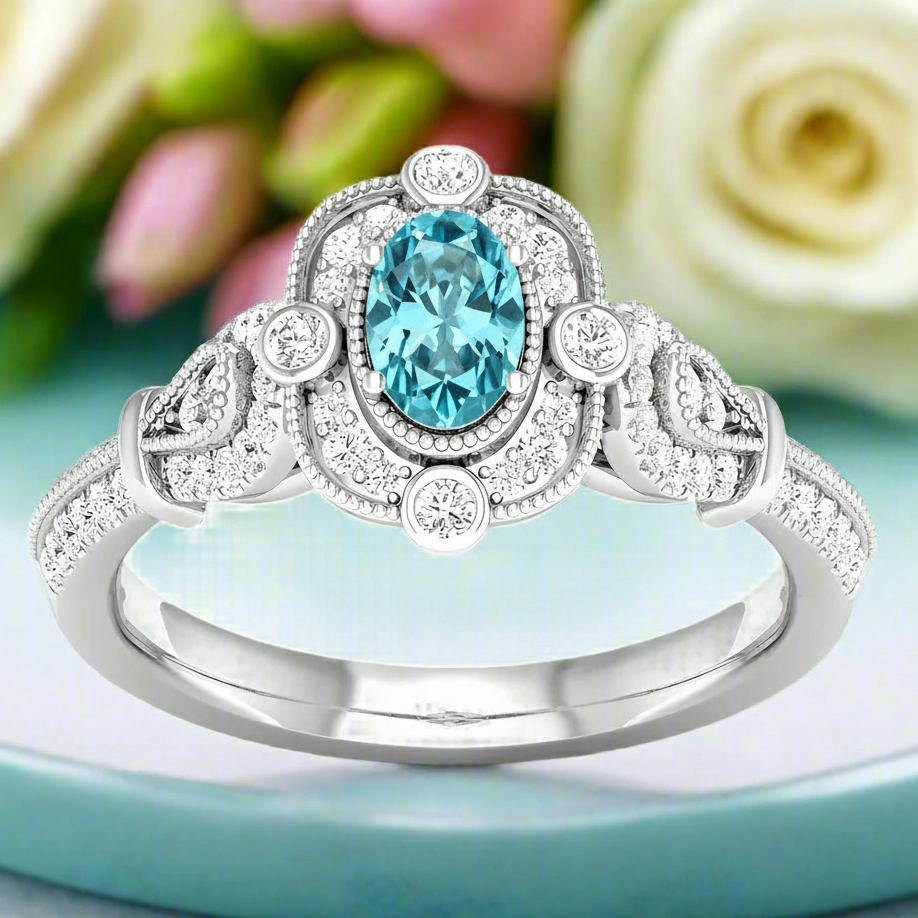 Silver ring with a blue gemstone on a light blue surface with flowers in the background