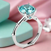 Silver ring with a blue gemstone on a pink and green background