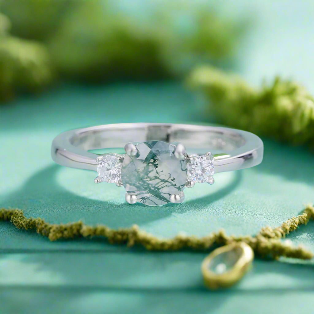 Silver ring with a central gemstone and two smaller stones on a light blue background