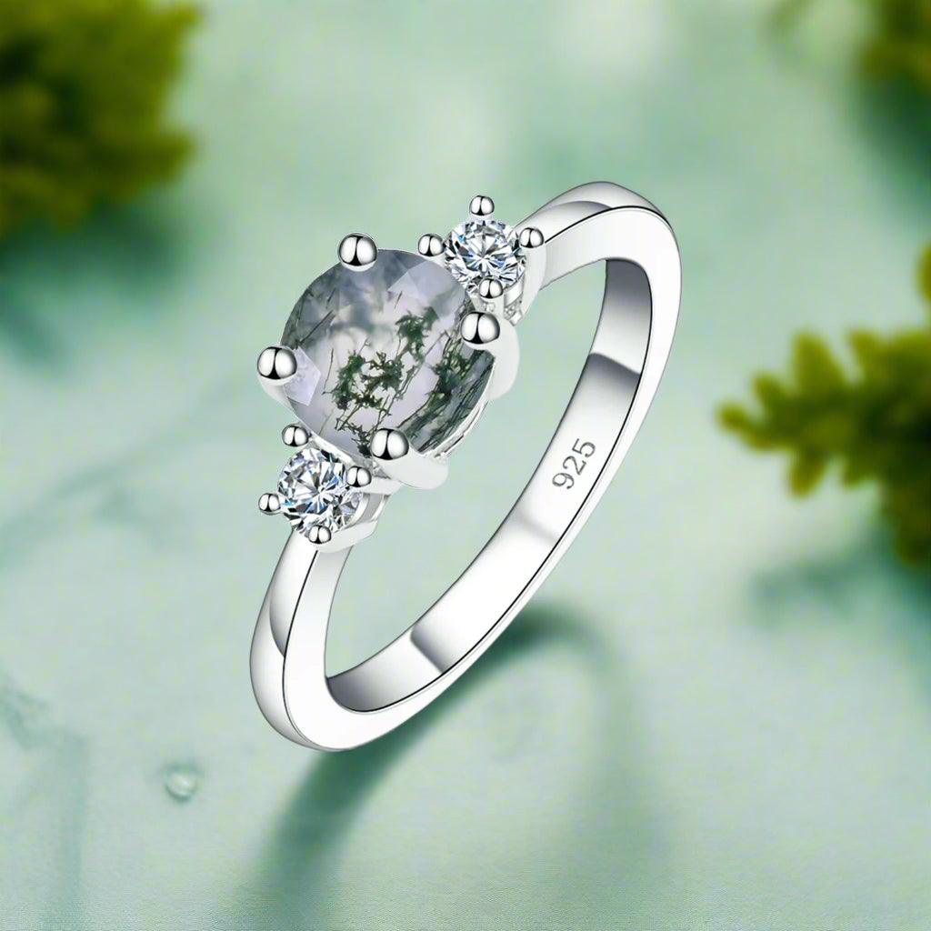 Silver ring with a green gemstone and diamonds on a white background