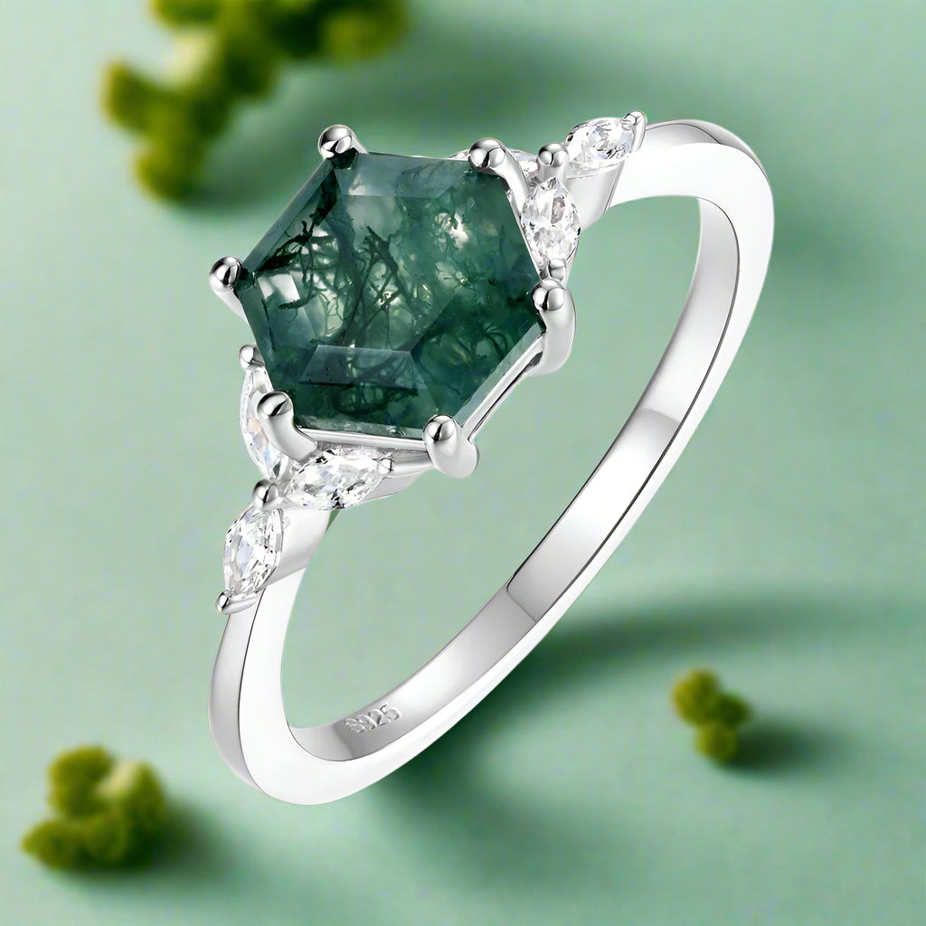 Silver ring with a green gemstone and diamonds on a white background