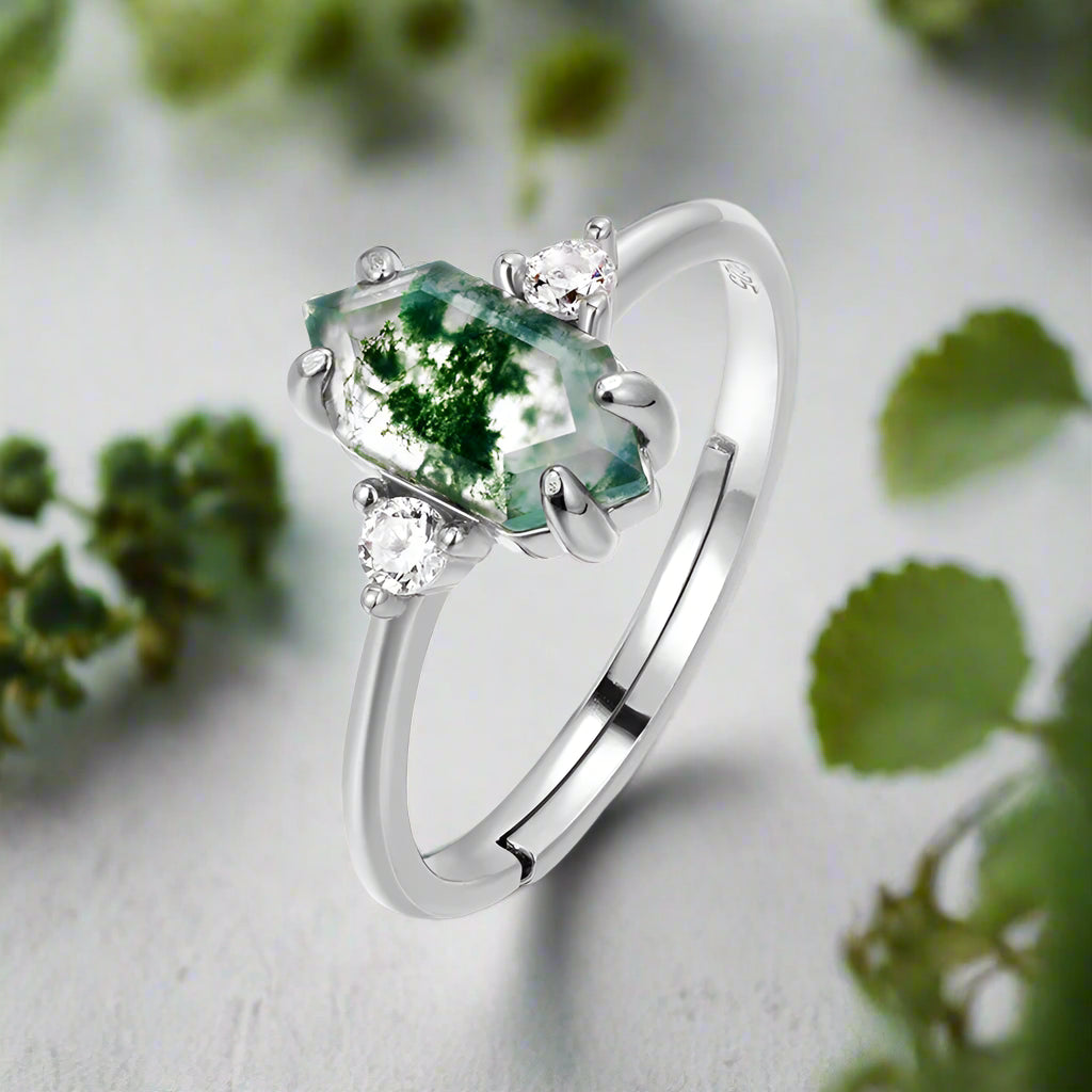 Silver ring with a green gemstone and small diamonds on a white background