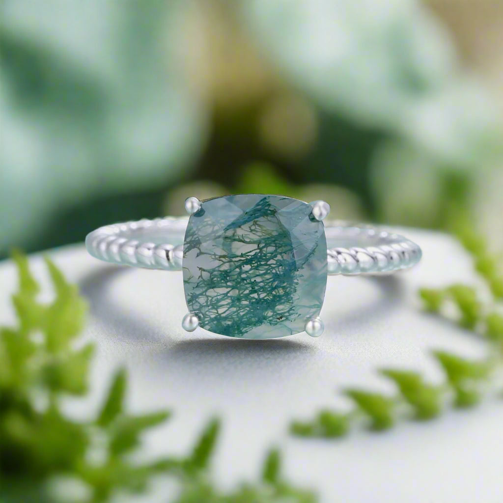Silver ring with a green gemstone on a light blue background