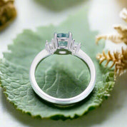 Silver ring with a green gemstone on a light blue background