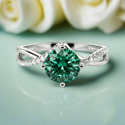 Silver ring with a green gemstone on a light green background with white roses.
