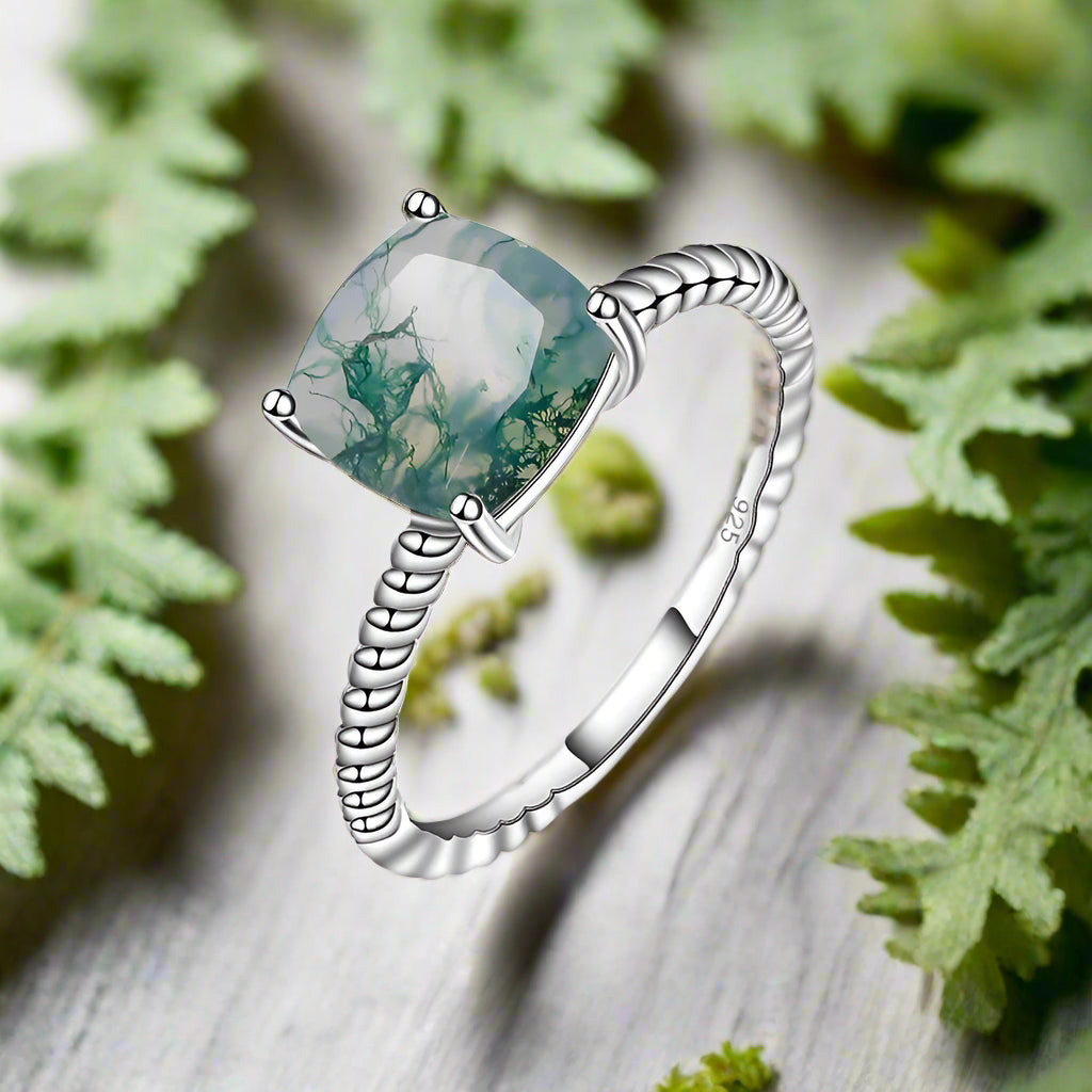 Silver ring with a green gemstone on a white background